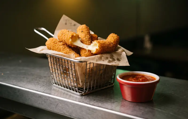 Basket of golden mozzarella sticks with one pulled open